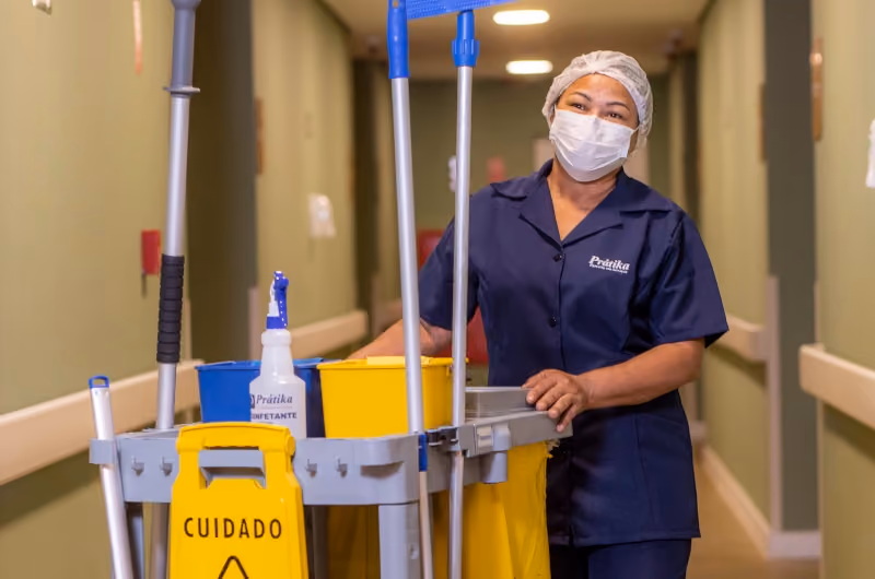 Profissional da Prátika com carrinho de limpeza em corredor hospitalar